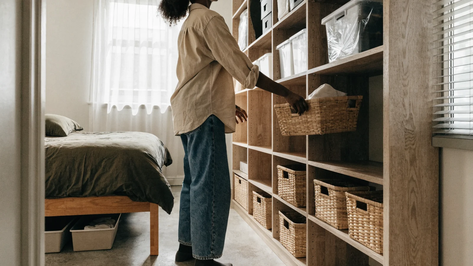 Home utility products for apartments stored by access frequency on vertical shelving and beneath a bed